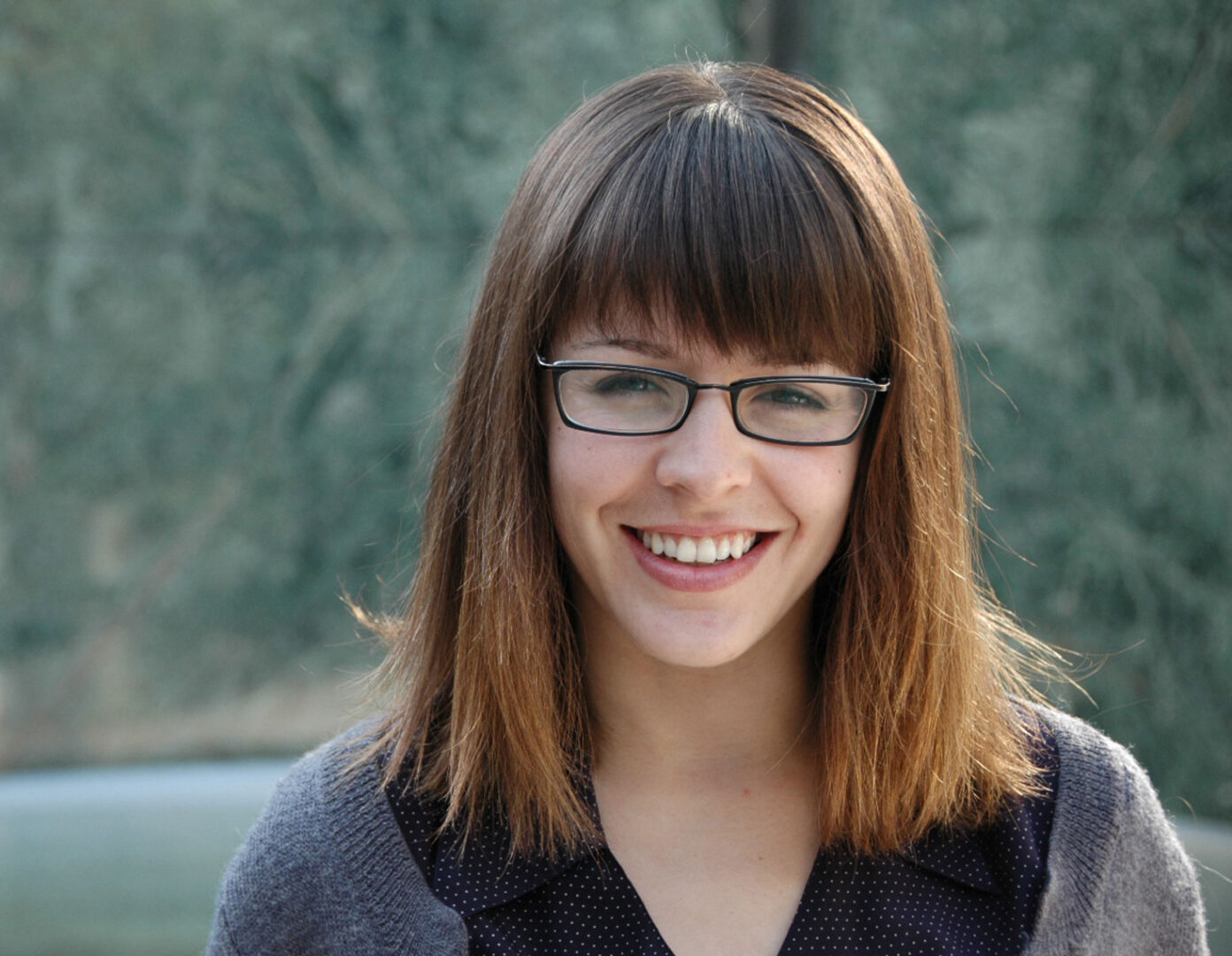 colored headshot photograph of woman with bangs and glasses